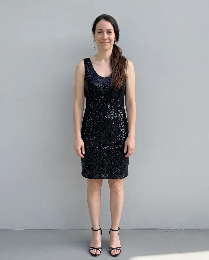 The same woman in a black sequin cocktail dress and strappy heels