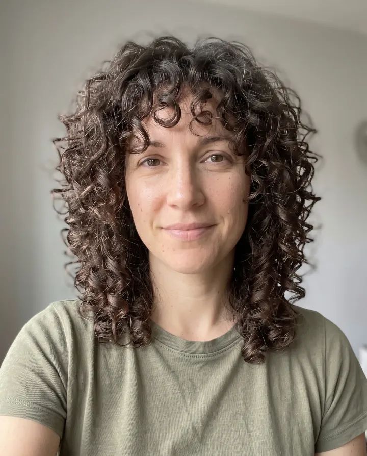 The same woman with a curly shag and curtain bangs