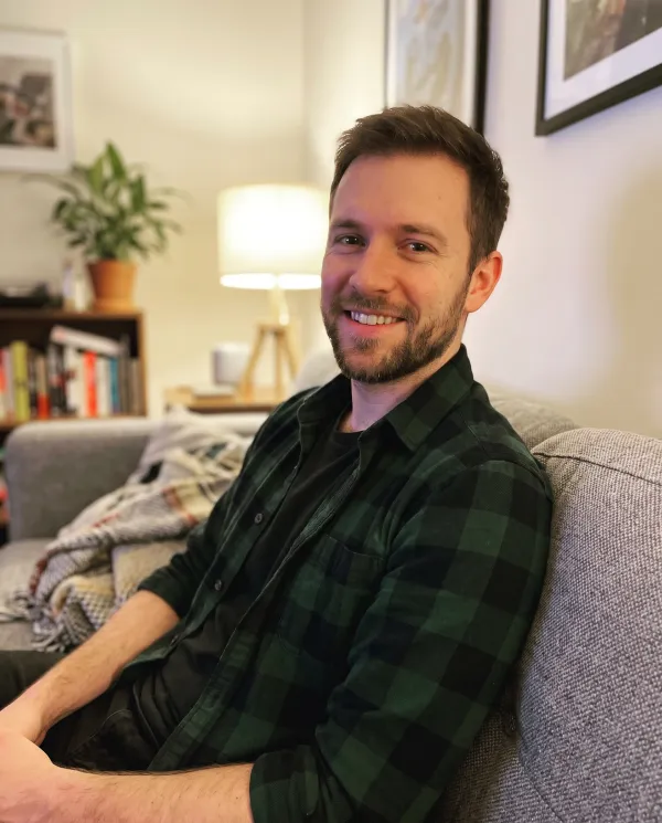 A man in a green flannel shirt on a grey sofa