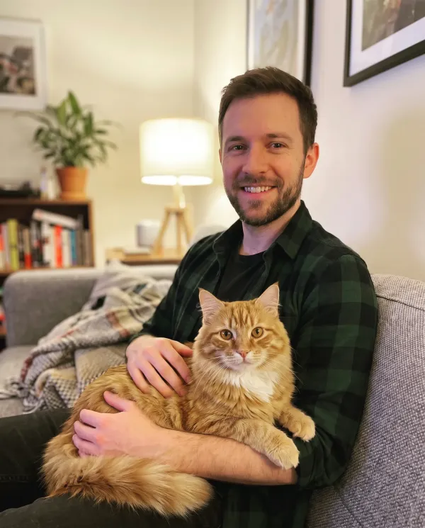 The man on the sofa with the orange tabby cat on his lap