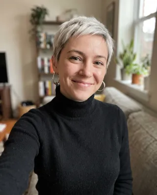 A selfie of a woman with a platinum pixie cut in a black turtleneck