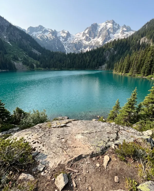 A turquoise alpine lake with a flat rock in the foreground