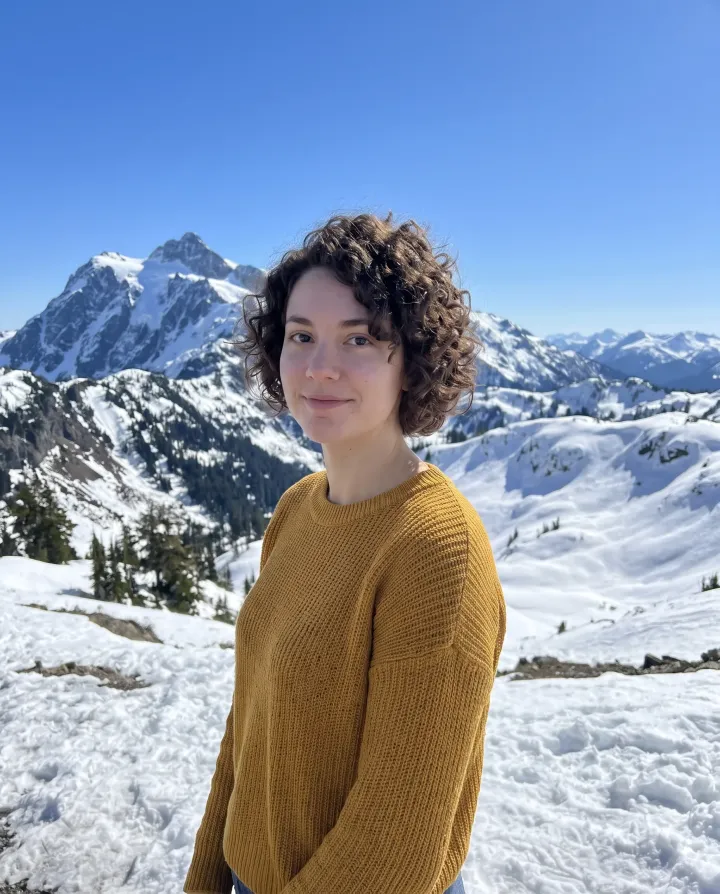The woman in front of snowy mountains on a clear day