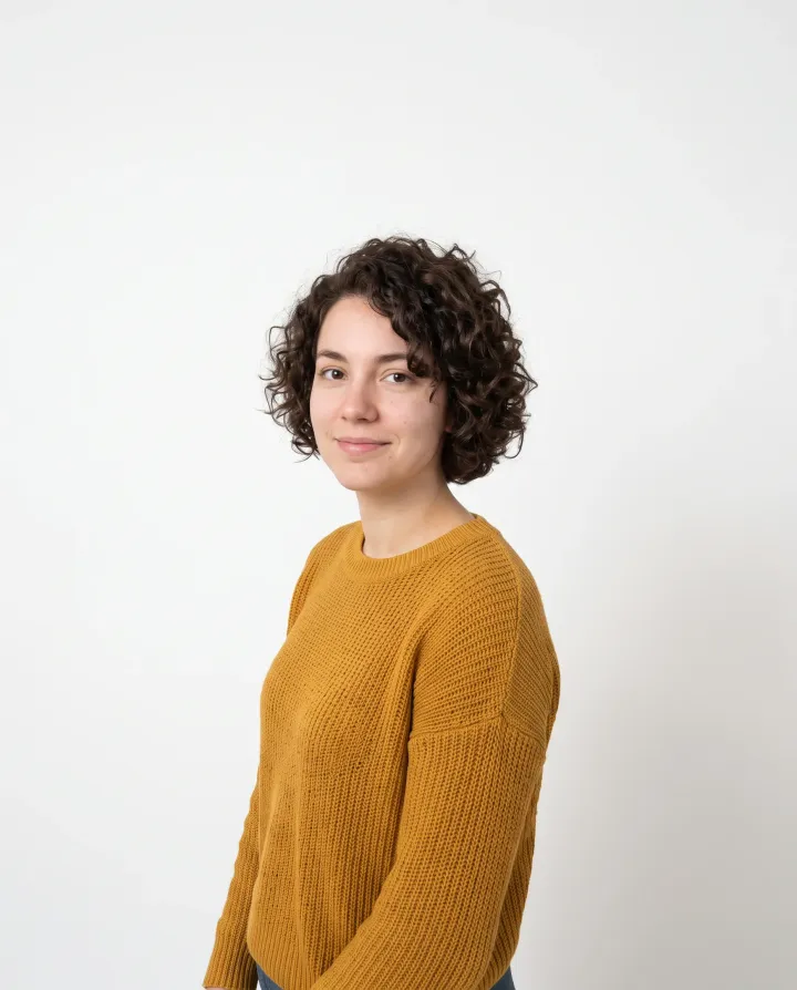 The woman in the mustard sweater against a plain white backdrop