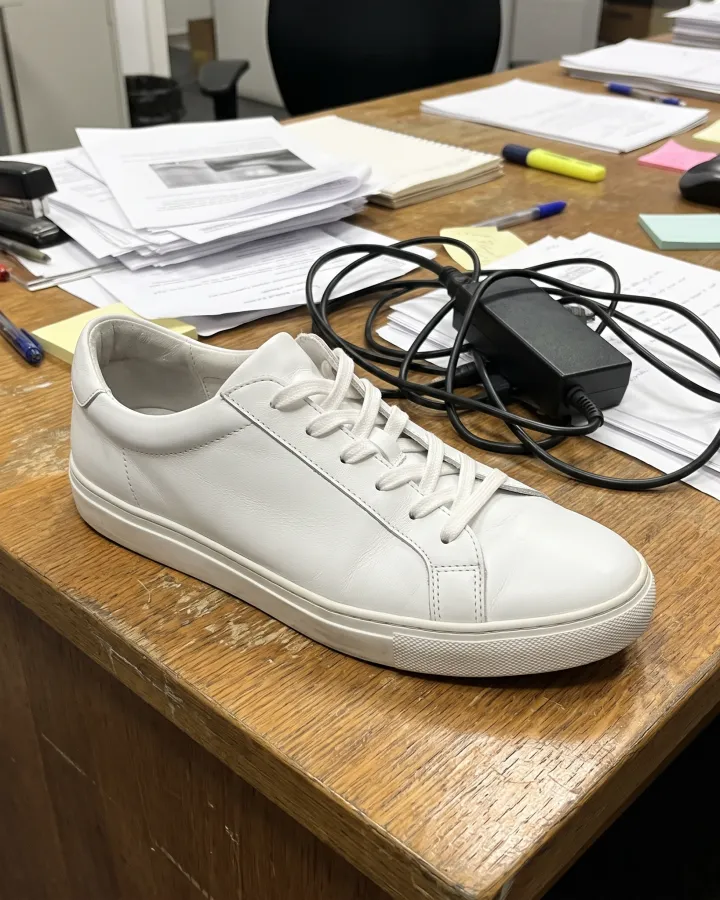 A white sneaker on a cluttered office desk