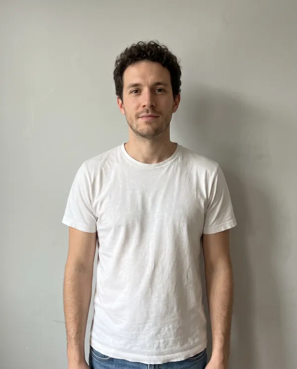 A man in a white t-shirt against a light grey wall