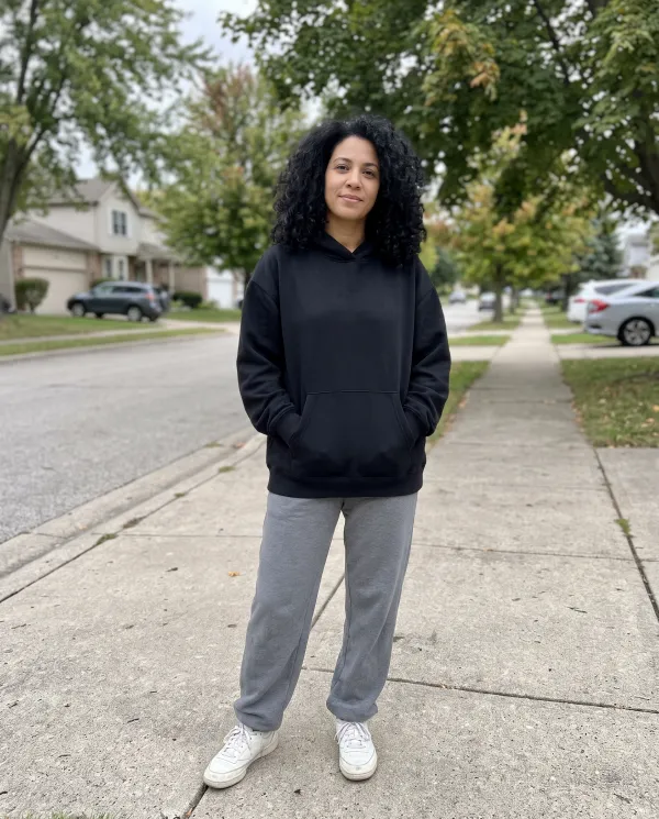 A woman in a black hoodie and grey sweatpants on a residential street