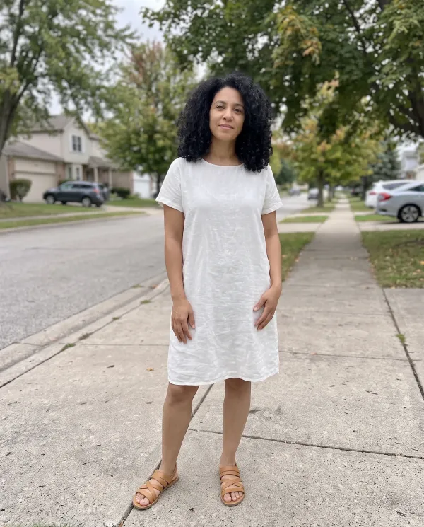 The same woman in a white linen summer dress and tan sandals