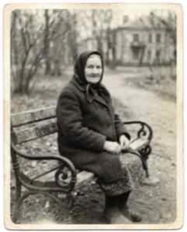 A blurry black-and-white photo of an elderly woman in a headscarf on a bench