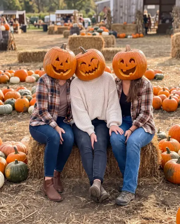 The same three friends on the hay bales, each with a different jack-o'-lantern head
